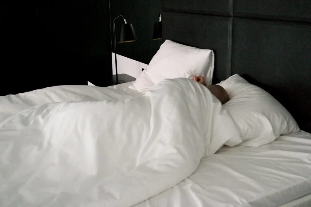 Une personne qui dort dans un lit de chambre d'hôtel